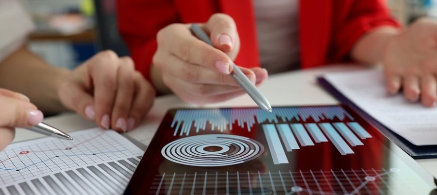 Business women studying charts and diagrams on digital tablet closeup